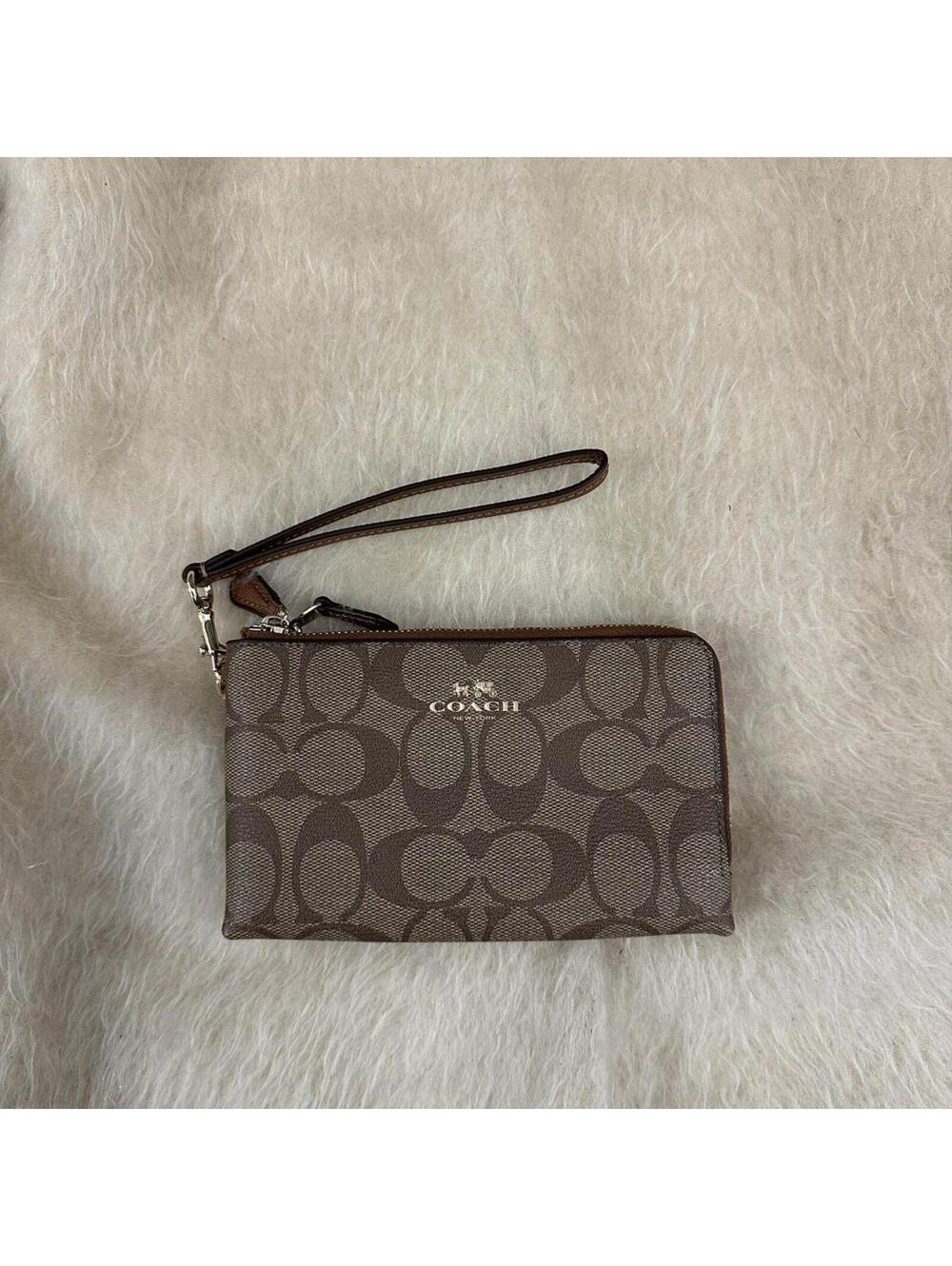 Brown Coach wristlet with zipper closure and leather details